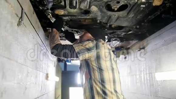 汽车服务机械师站在检查坑里用扳手工作视频的预览图