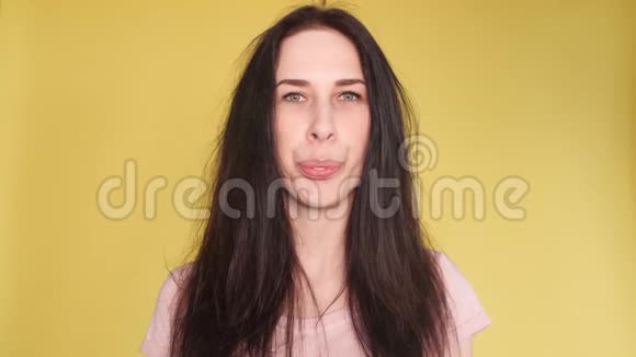 头发凌乱的漂亮女孩在黄色背景上吹口香糖视频的预览图