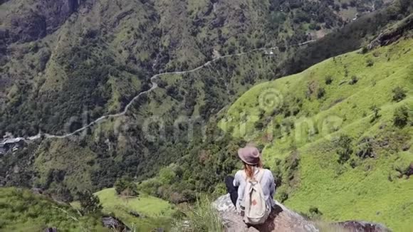 女旅行者坐在山上的大石头上视频的预览图