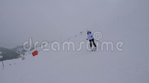 滑雪者在冬天的雾中滑下山坡视频的预览图