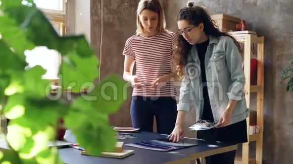 年轻女性站在桌子附近在桌子上放照片用智能手机拍摄平面他们在分享视频的预览图