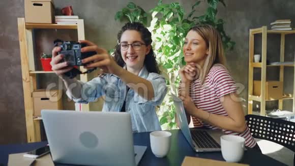 创意设计师们坐在现代办公室里一起摆姿势自拍他们用照相机笑着视频的预览图