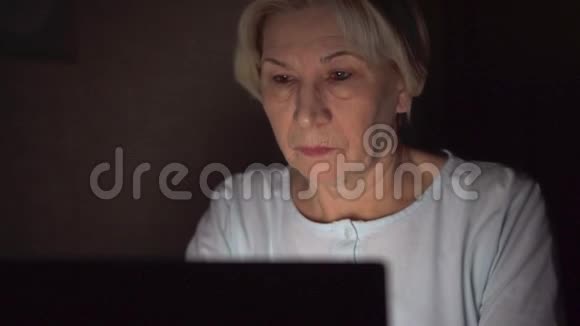 疲惫的高级女商人深夜在笔记本电脑上工作劳累过度头痛视频的预览图