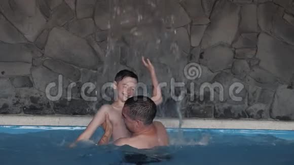 一个幸福的家庭父子俩在游泳池里玩耍视频的预览图