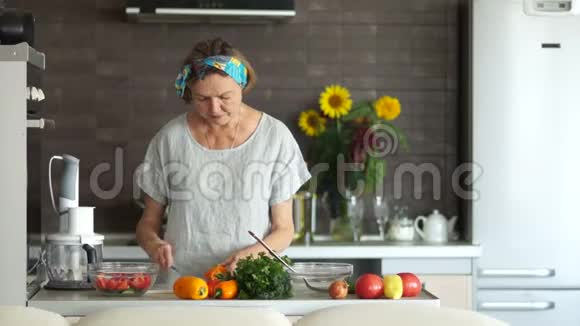 一位老妇人正在切胡椒作沙拉现代厨房内部健康的生活方式母亲节视频的预览图