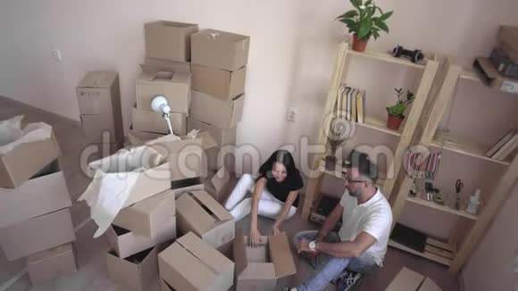 这对夫妇把东西放进盒子里搬到一个新家年轻夫妇轻松地搬进了一所带着未包装盒子的新房子视频的预览图