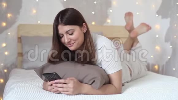 美丽的女孩喜欢手机躺在床上心情很好高清高清视频的预览图