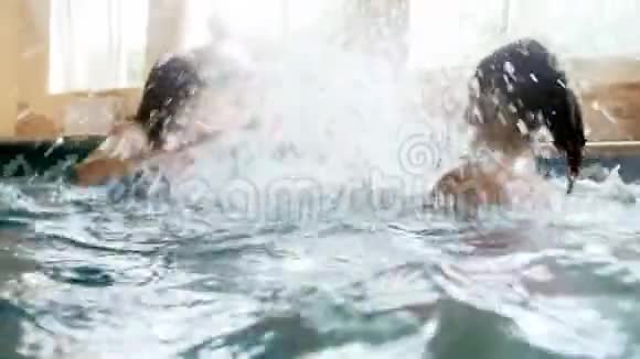 两名少女在室内游泳池玩耍和泼水的4K镜头视频的预览图