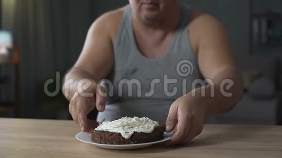 成年超重男子狼吞虎咽地吃蛋糕舔手指糖尿病垃圾食品视频的预览图