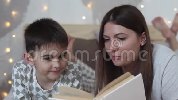 一位留着长发的美丽母亲给躺在床上的小男孩读了一本书吻了他一个好心情高清高清视频的预览图