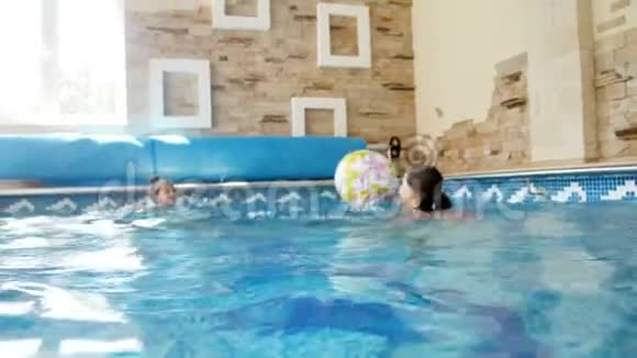 两名少女在室内游泳池玩彩色沙滩球的4k录像视频的预览图
