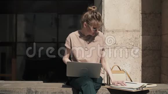 漂亮的年轻女性夏天在外面用笔记本电脑和书学习视频的预览图