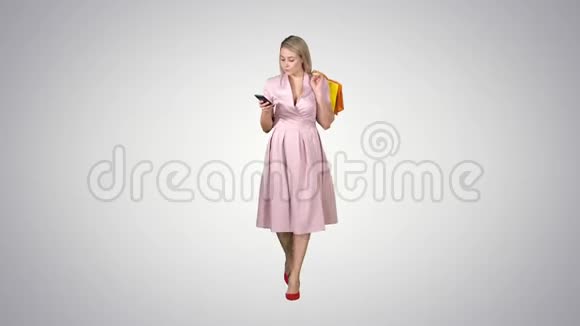 购物妇女带着袋子在智能手机上发短信而在梯度背景下行走视频的预览图