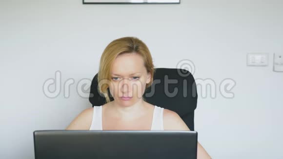 一个女人用她的笔记本电脑坐在桌子旁突然感到震惊和厌恶人类的情感网瘾视频的预览图