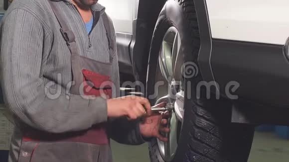 汽车机械手是一个车轮在汽车上扭曲的手动螺栓由起重设备提高视频的预览图