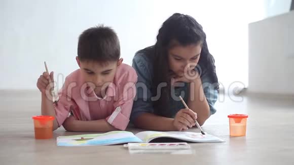 开心的小哥哥小姐姐在相册里画着颜料躺在地上笑着总体计划视频的预览图