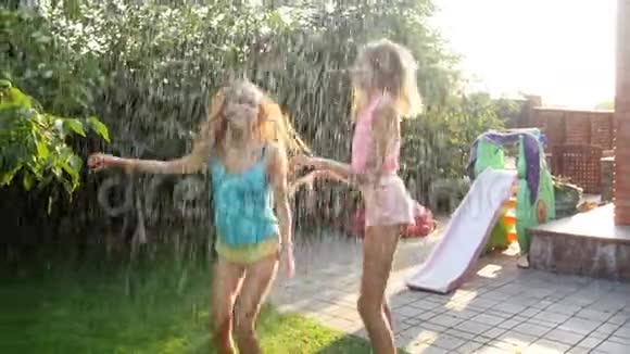 两个十几岁的女孩在后院花园水管溅起的水花下跳舞和跳跃的4k视频视频的预览图