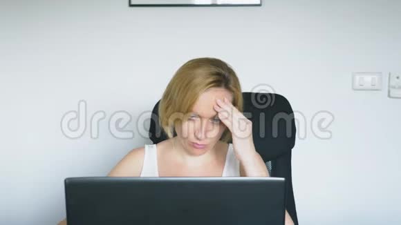 一个女人用她的笔记本电脑坐在桌子旁愤怒和恼怒人类的情感网瘾视频的预览图