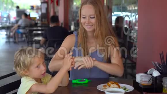 年轻女子和儿子在咖啡馆里用洗手液视频的预览图