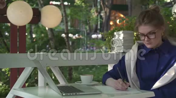 年轻的白种人女商人在一家夏季咖啡馆写作业务战略视频的预览图