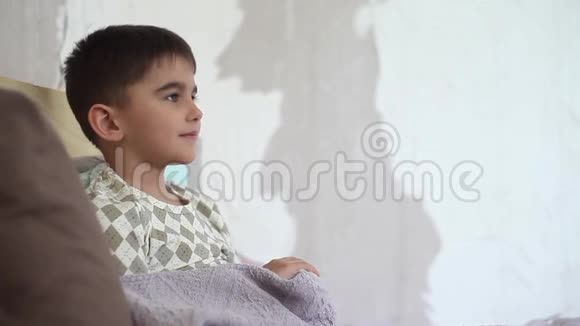 一个小男孩咳嗽用毯子盖上被子视频的预览图