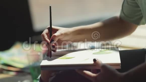 这位女艺术家手里拿着画笔在相册里画画视频的预览图
