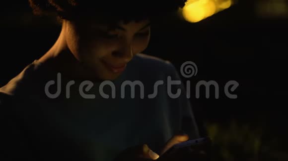 微笑女性在智能手机上阅读男友信息夜街女孩视频的预览图