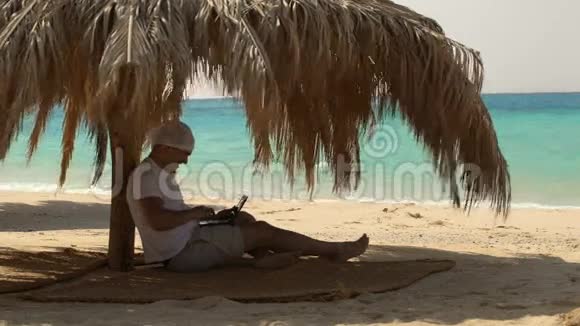 在海滩上用笔记本电脑的人视频的预览图