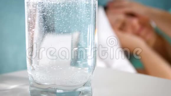 在床上疼痛的妇女旁边的床头桌上放一杯水和阿司匹林的特写慢动作视频视频的预览图