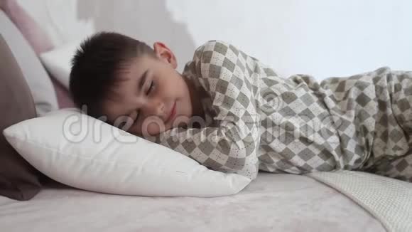 穿着睡衣躺在床上睡着的小男孩视频的预览图
