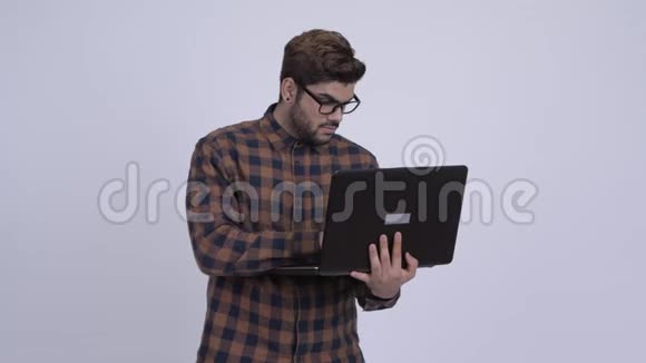 年轻的留胡子的印度嬉皮士在使用笔记本电脑时思考视频的预览图
