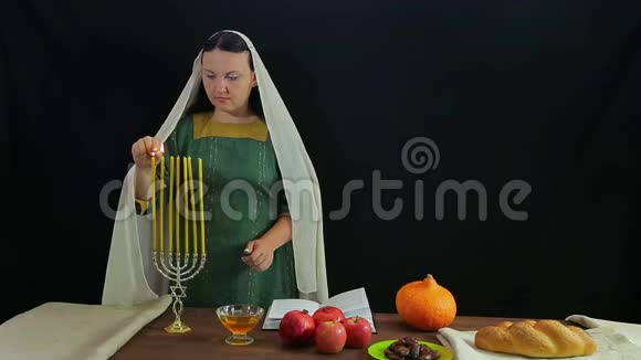 一位犹太妇女在节日的烛台上点燃蜡烛以纪念罗什哈珊视频的预览图