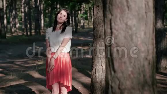 一位年轻的美女站在阳光下的树林中抚摸着她的头发平静地呼吸着感觉到视频的预览图