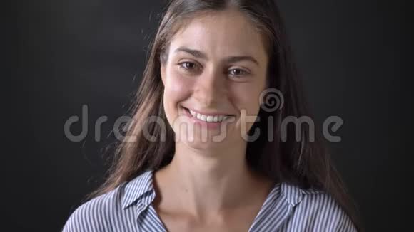 穿着条纹衬衫的快乐美女对着镜头微笑站在黑色背景下与世隔绝视频的预览图