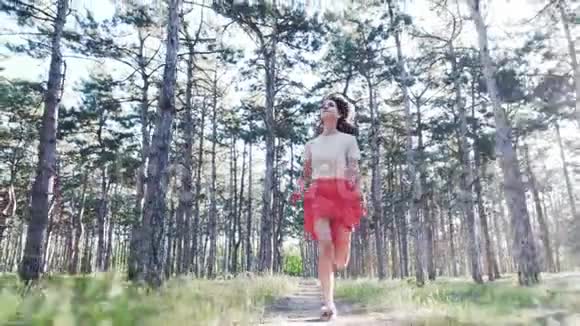 一个年轻漂亮的女人正快乐地沿着马路在无数的松树上奔跑慢动作视频的预览图
