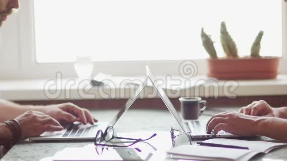 自由职业者在坐在笔记本电脑前工作一个在纸上做笔记第二个站起来关上视频的预览图