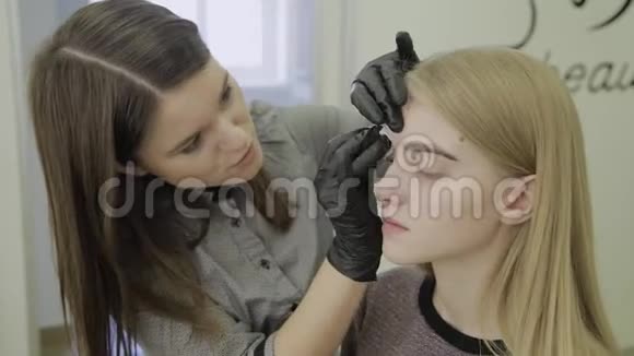 在染色程序后用棉盘擦拭一个年轻女孩的眉毛视频的预览图
