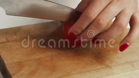 公寓里的厨房年轻女子用刀子在木板上切西红柿餐桌上切蔬菜视频的预览图