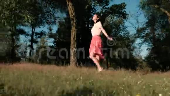 一个年轻漂亮的女人在树林里快乐地走着摸着她的裙子跳着举起她的手去摸视频的预览图