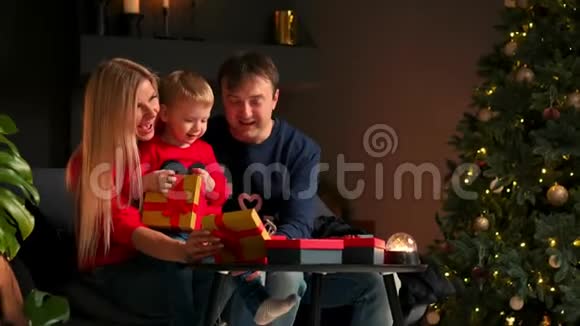 幸福家庭的肖像在晚上打开圣诞礼物盒假期概念惊喜快乐视频的预览图