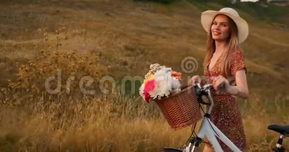 穿着中规中矩的女孩在田野里骑着自行车和鲜花视频的预览图