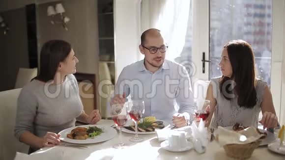 在餐厅里有两位迷人的女士陪伴的男性提议为会议举起一杯红酒视频的预览图