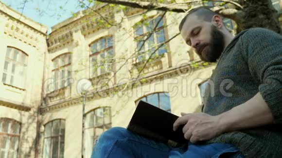 那个长胡子的人坐在公园里看书但他接到一个电话视频的预览图