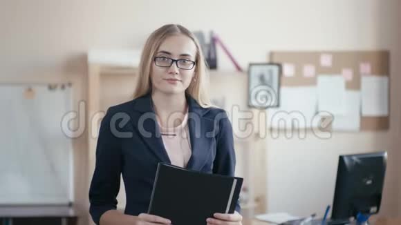 呼叫中心员工在办公室工作一个金发戴眼镜的年轻女孩站在办公室里手里拿着一个视频的预览图