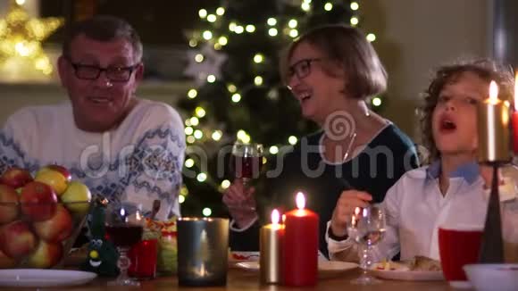 圣诞餐桌上的家庭圈里快乐的女人感恩节的大家庭晚上的灯光蜡烛视频的预览图