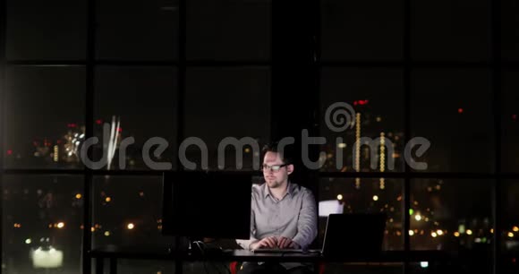办公室经理男子正在加班深夜在键盘上打字视频的预览图