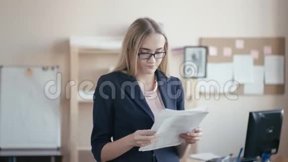 呼叫中心员工在办公室工作一个金发戴眼镜的年轻女孩正站在办公室里手里拿着视频的预览图