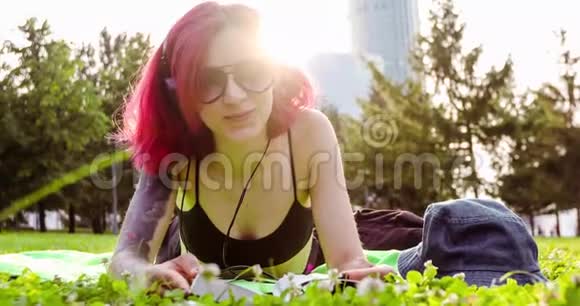 红头发的女孩躺着放松的公园草地视频的预览图