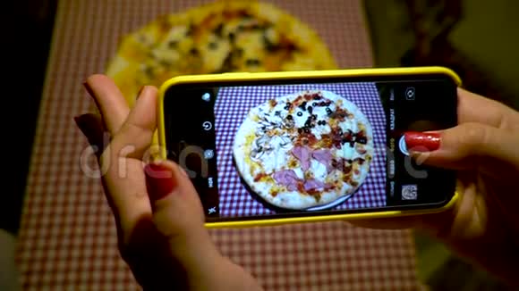 年轻女人用智能手机拍披萨女人拍披萨的照片视频的预览图