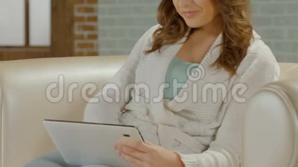 漂亮的女性在沙发上放松在平板电脑上和男朋友聊天特写镜头视频的预览图